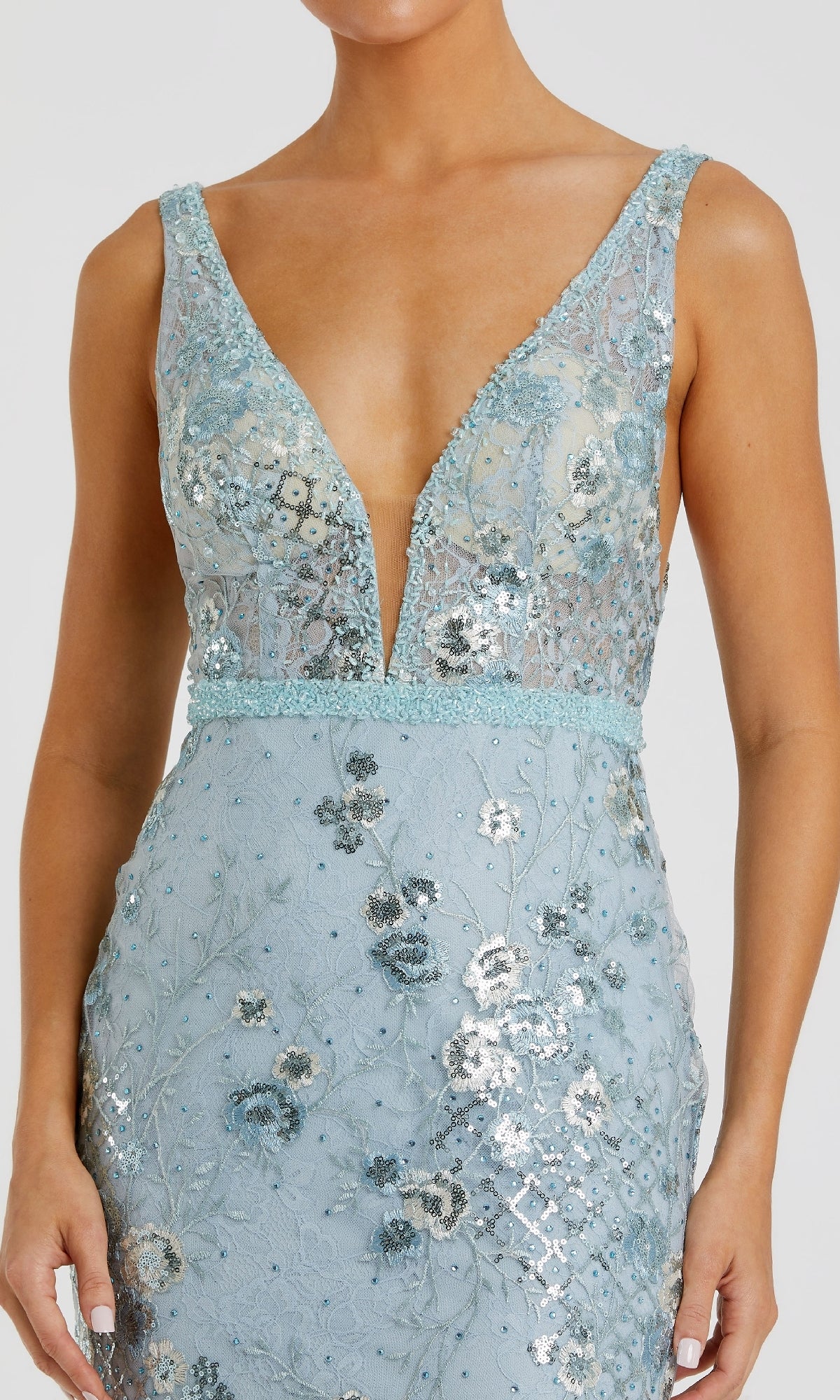 A person wearing the Mac Duggal 67481 long floral-print formal dress, a sleeveless, deep V-neck evening gown in light blue with intricate silver and blue floral embroidery.